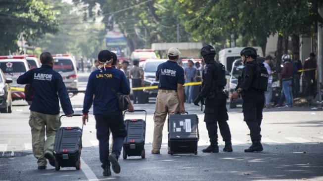 Petugas menyisir lokasi ledakan bom yang terjadi di tiga lokasi di Surabaya, Minggu (13/5/2018) [AFP]